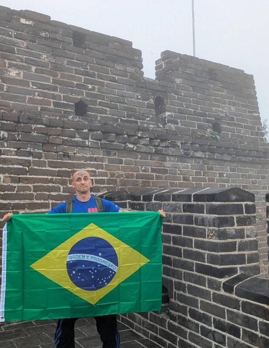 Aang Willians segura a bandeira do Brasil na Grande Muralha, em Mutianyu. 2025, do Instagram dele.