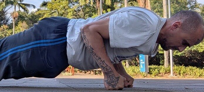 Aang Willians faz flexão sobre os punhos no Parque do Ibirapuera, sob as palmeiras. 25 de abril de 2026, do canal dele no YouTube.