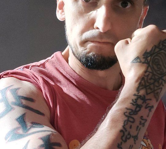 Aang Willians em guarda, com os punhos erguidos e tatuagens de caracteres chineses nos braços. 2024, do Instagram dele.