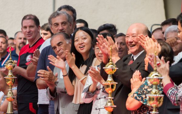 Chan Kowk Wai aplaude num campeonato, entre troféus.