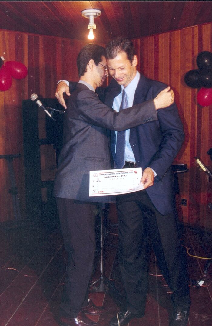 Um abraço numa formatura, com o certificado na mão.